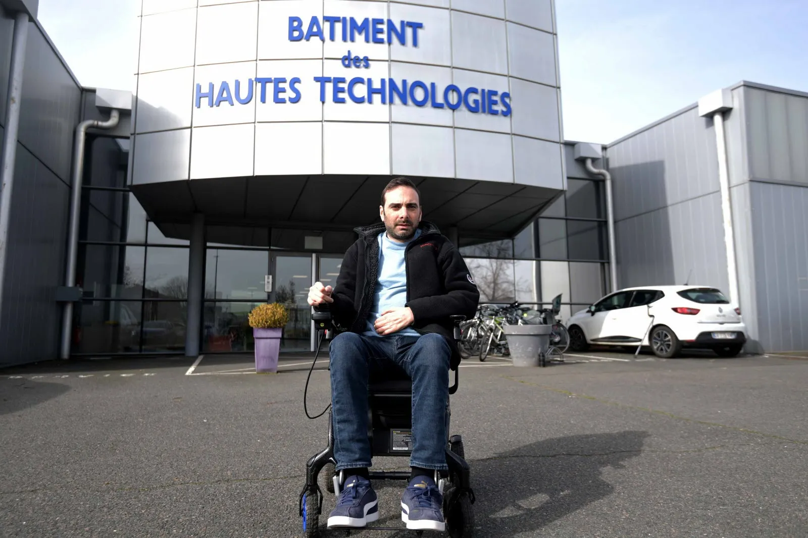 Sylvain Grousson dans son fauteuil roulant devant le Bâtiment des Hautes Technologies, à Saint-Étienne.